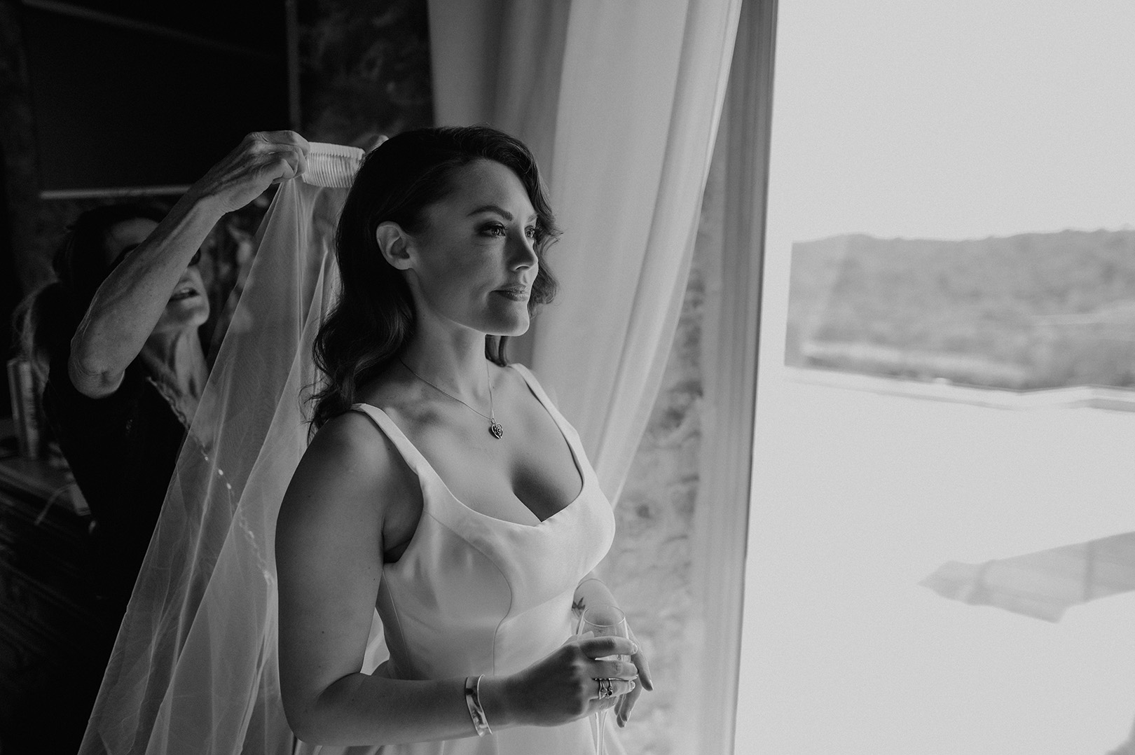 black-and-white-photo-of-bride-putting-her-veil-on